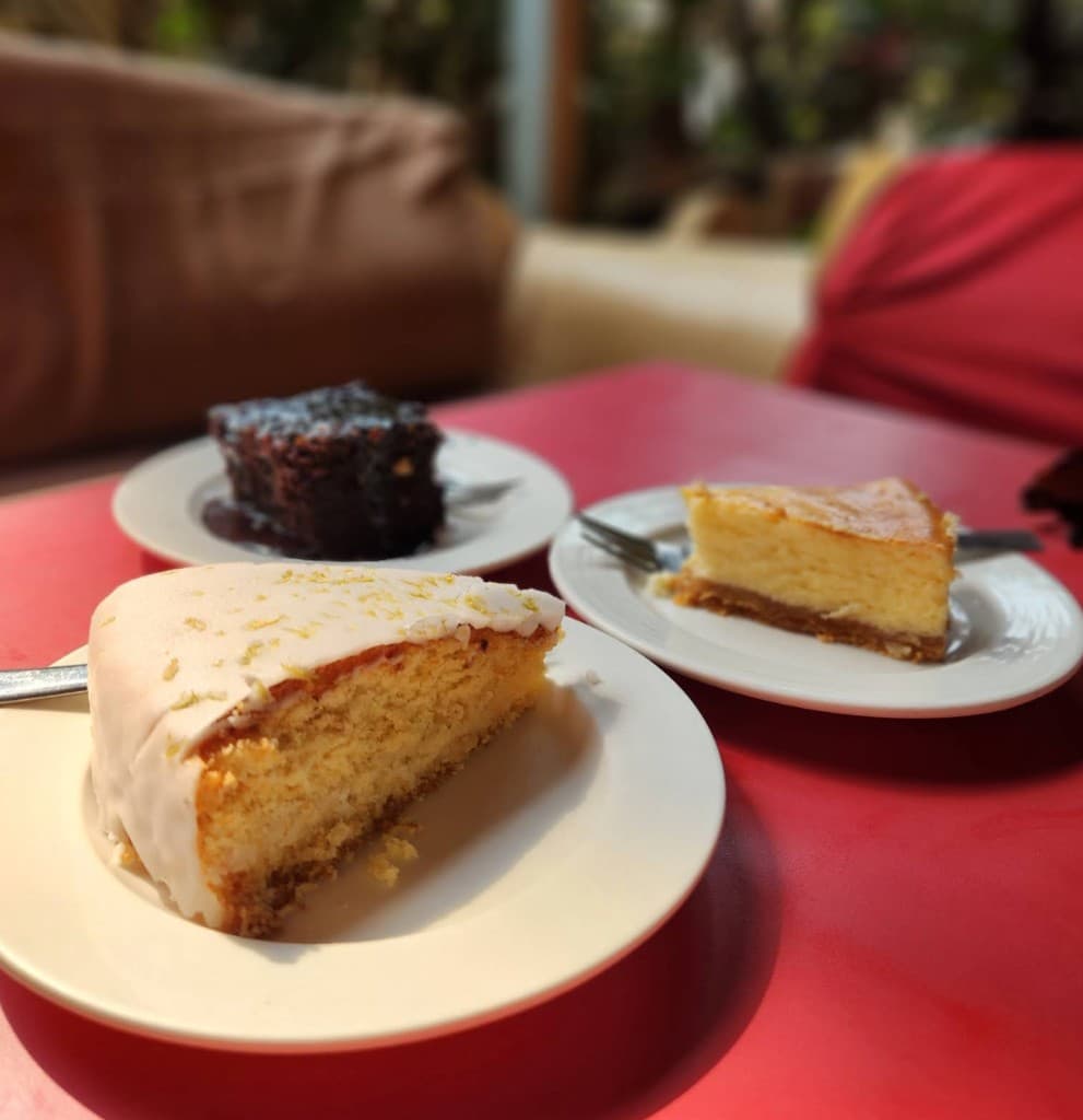Slices of lemon cake, cheesecake, and chocolate cake on a table at German Bakery, Anjuna