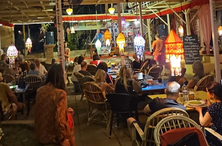 Evening crowd seated under lanterns at German Bakery, Anjuna